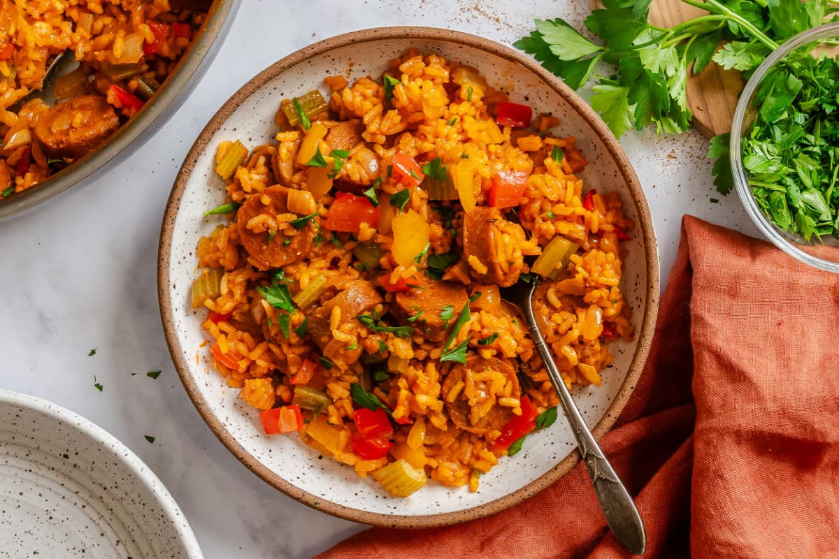 A plate of Cajun sausage and rice next to the skillet.