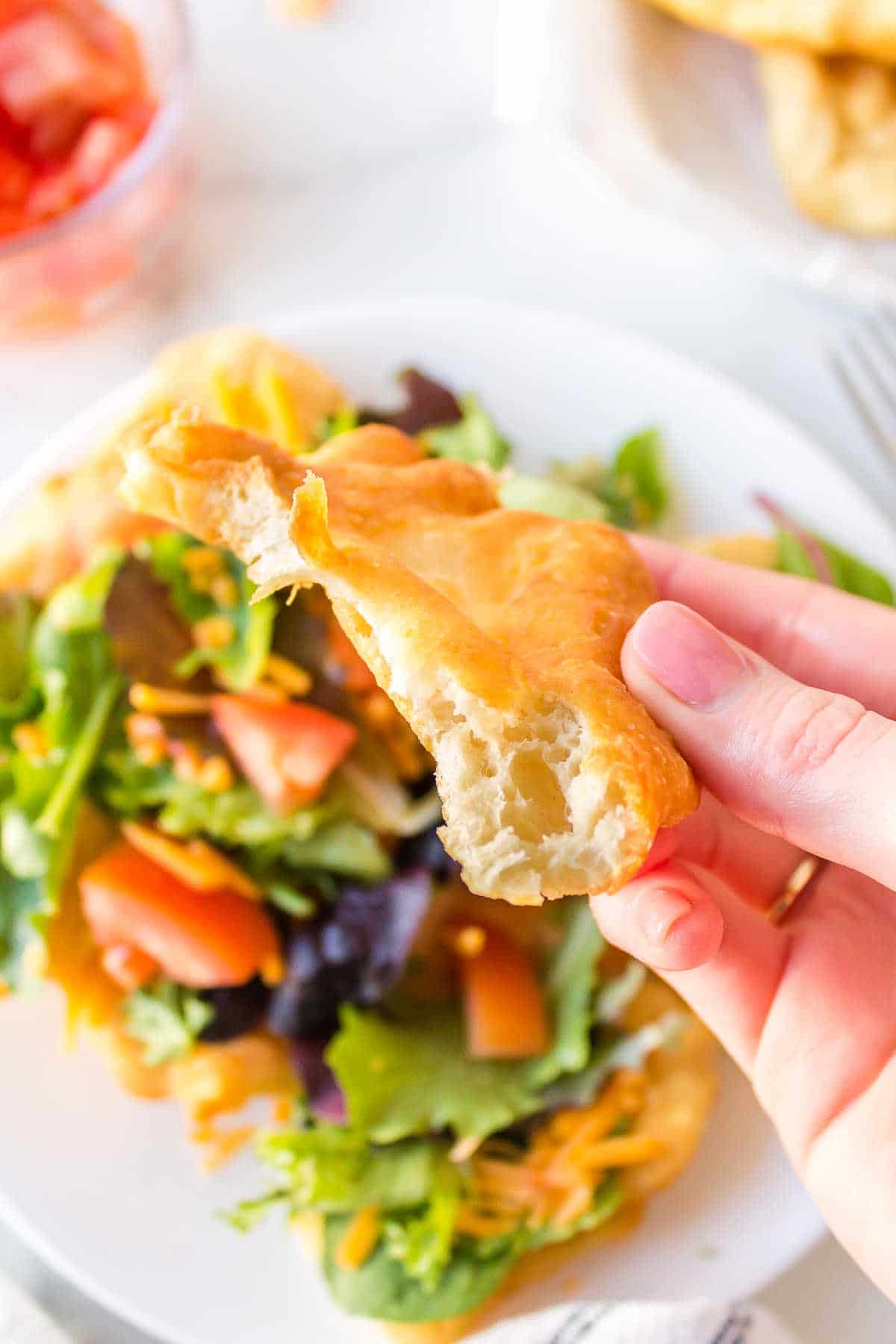 A piece of fry bread being held in one hand.