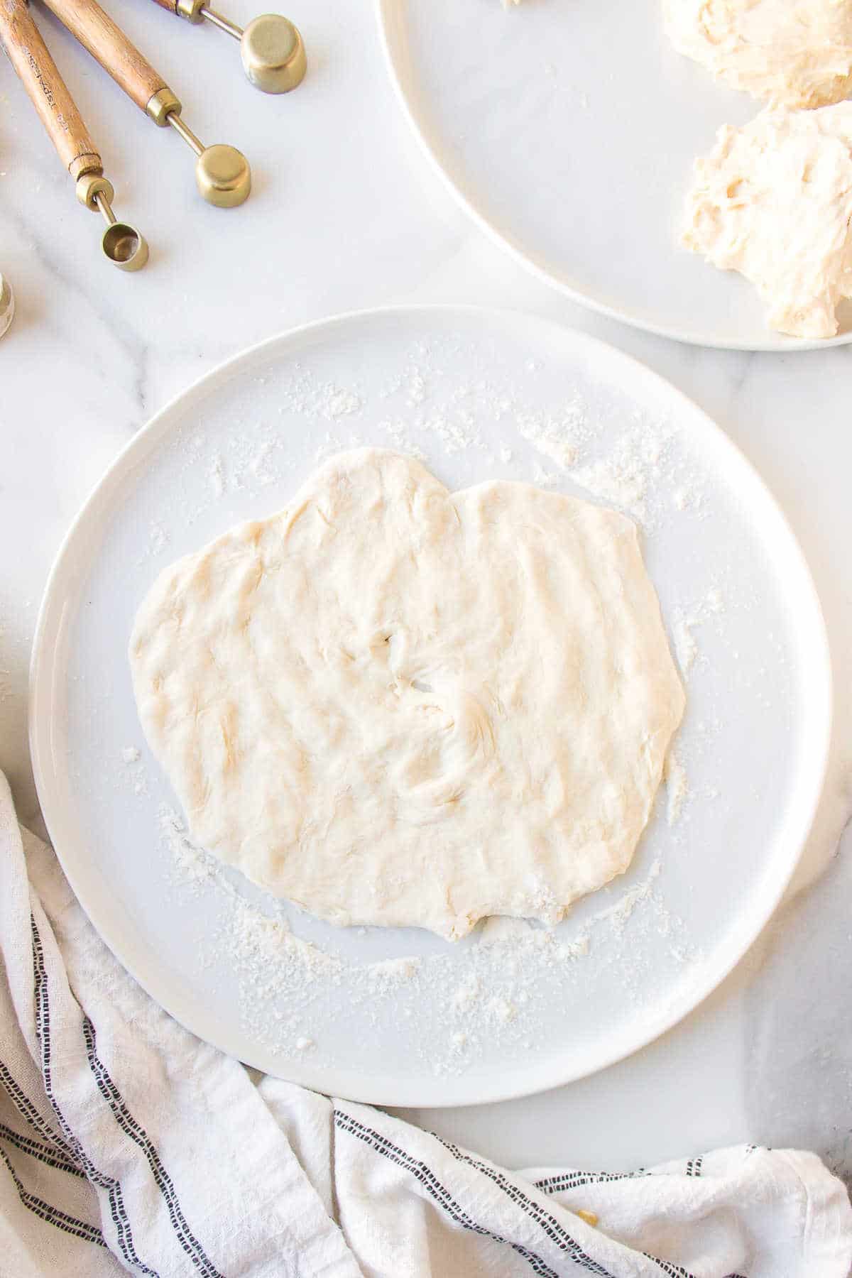 A piece of fry bread dough stretched out on a plate. 