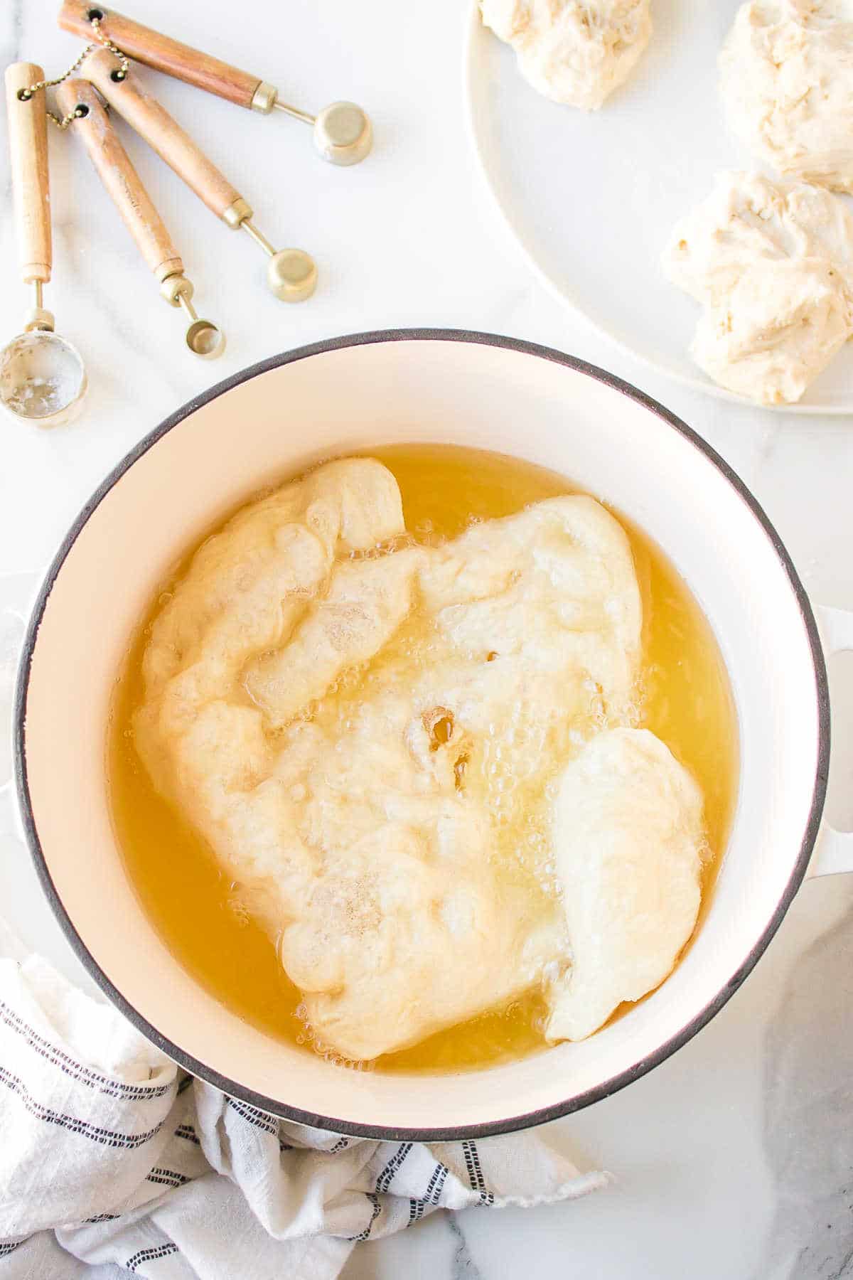 A piece of fry bread frying in a pot of oil.