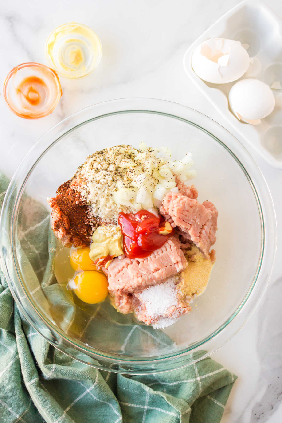 Ingredients for turkey burgers in a glass mixing bowl. 