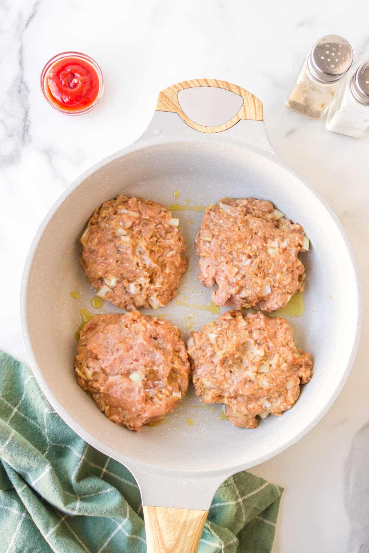 Four turkey burger patties in a skillet. 