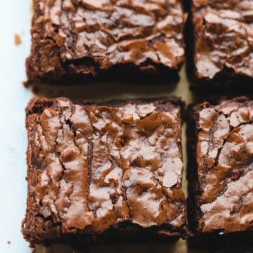 A row of cut baked brownies on parchment paper.