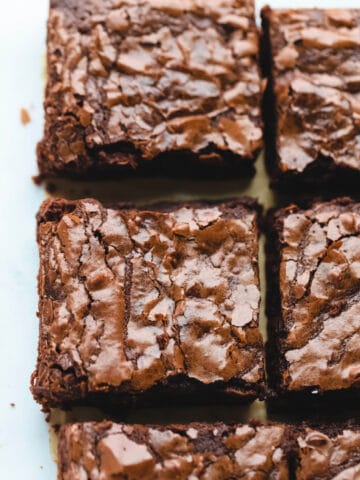 A row of cut baked brownies on parchment paper.
