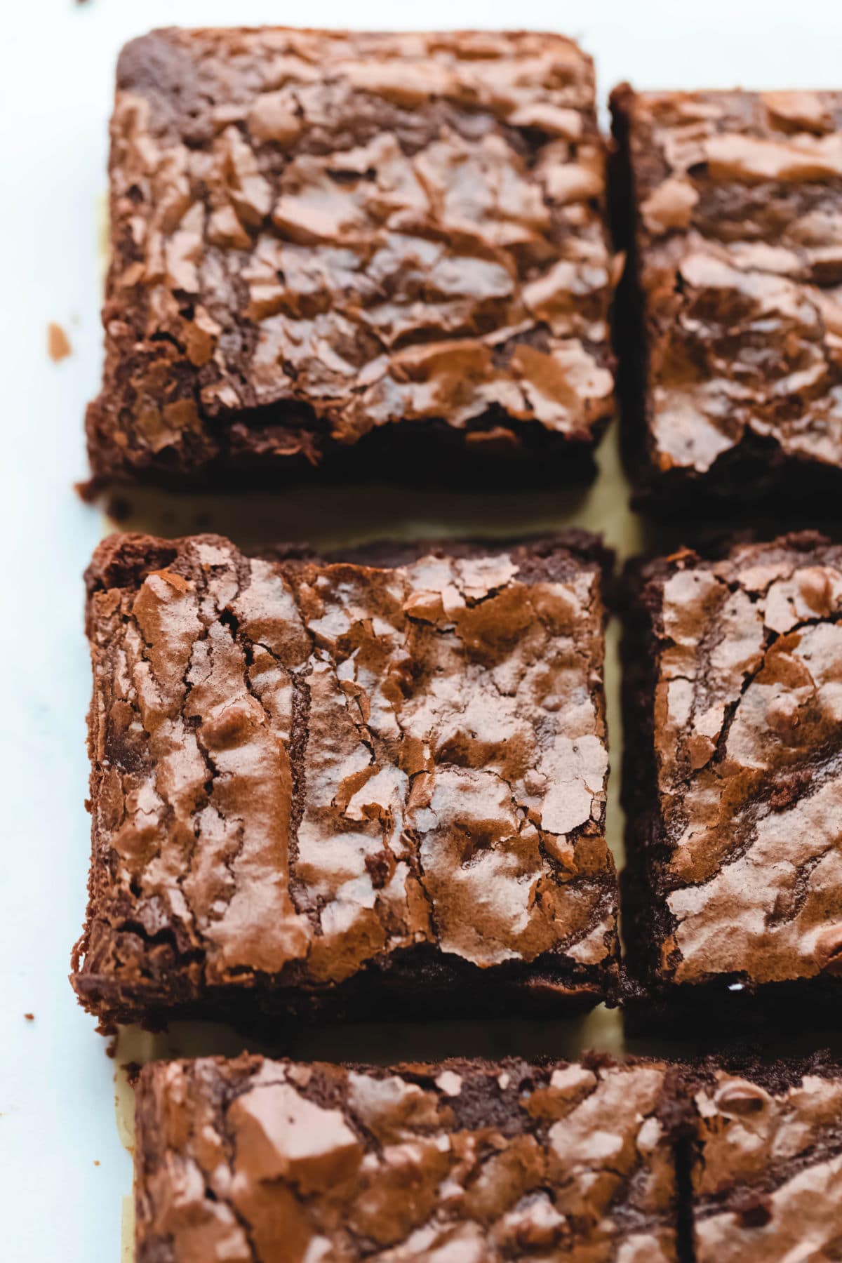 A row of cut baked brownies on parchment paper.