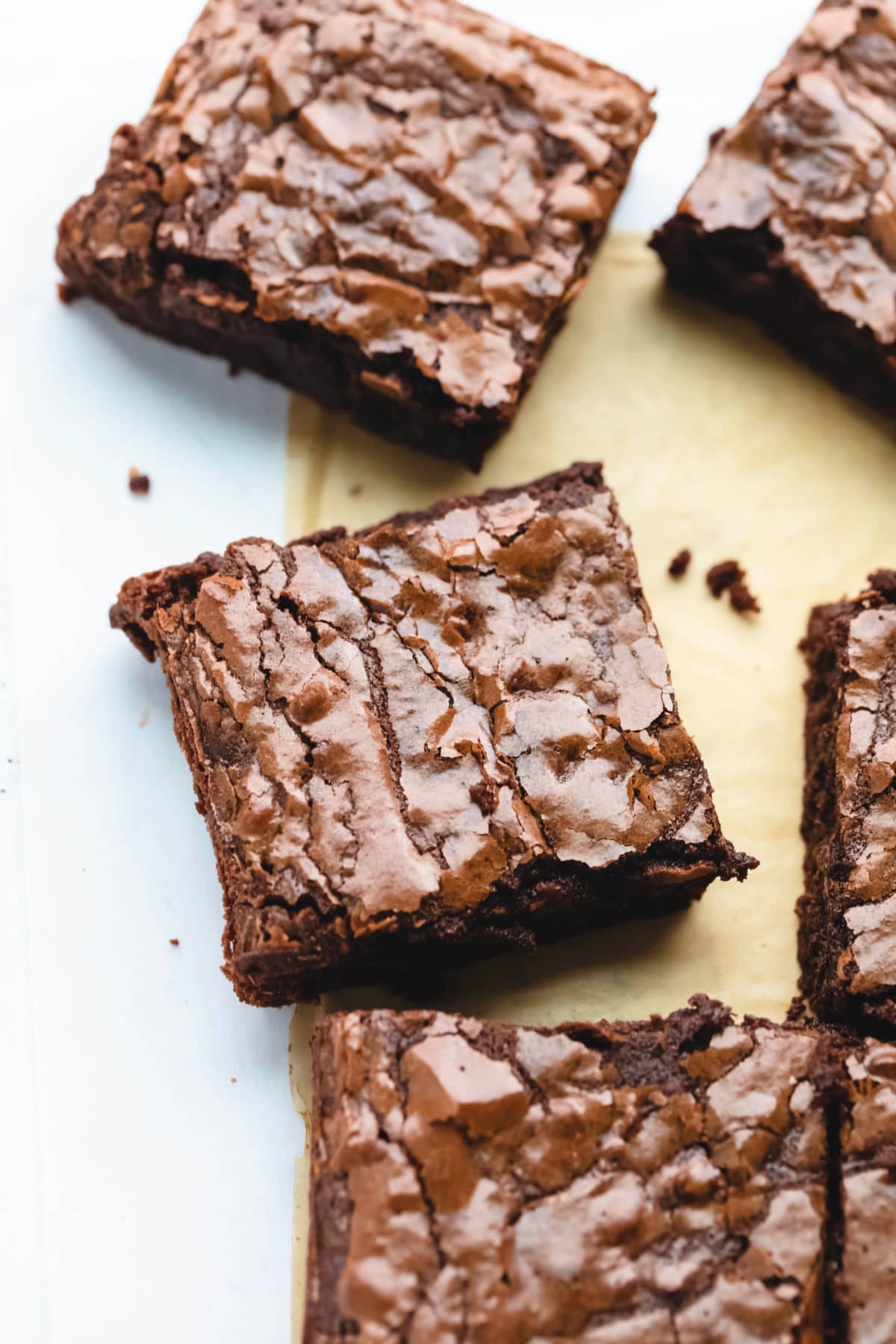 Cut brownies at an angle on brown and white parchment paper. 