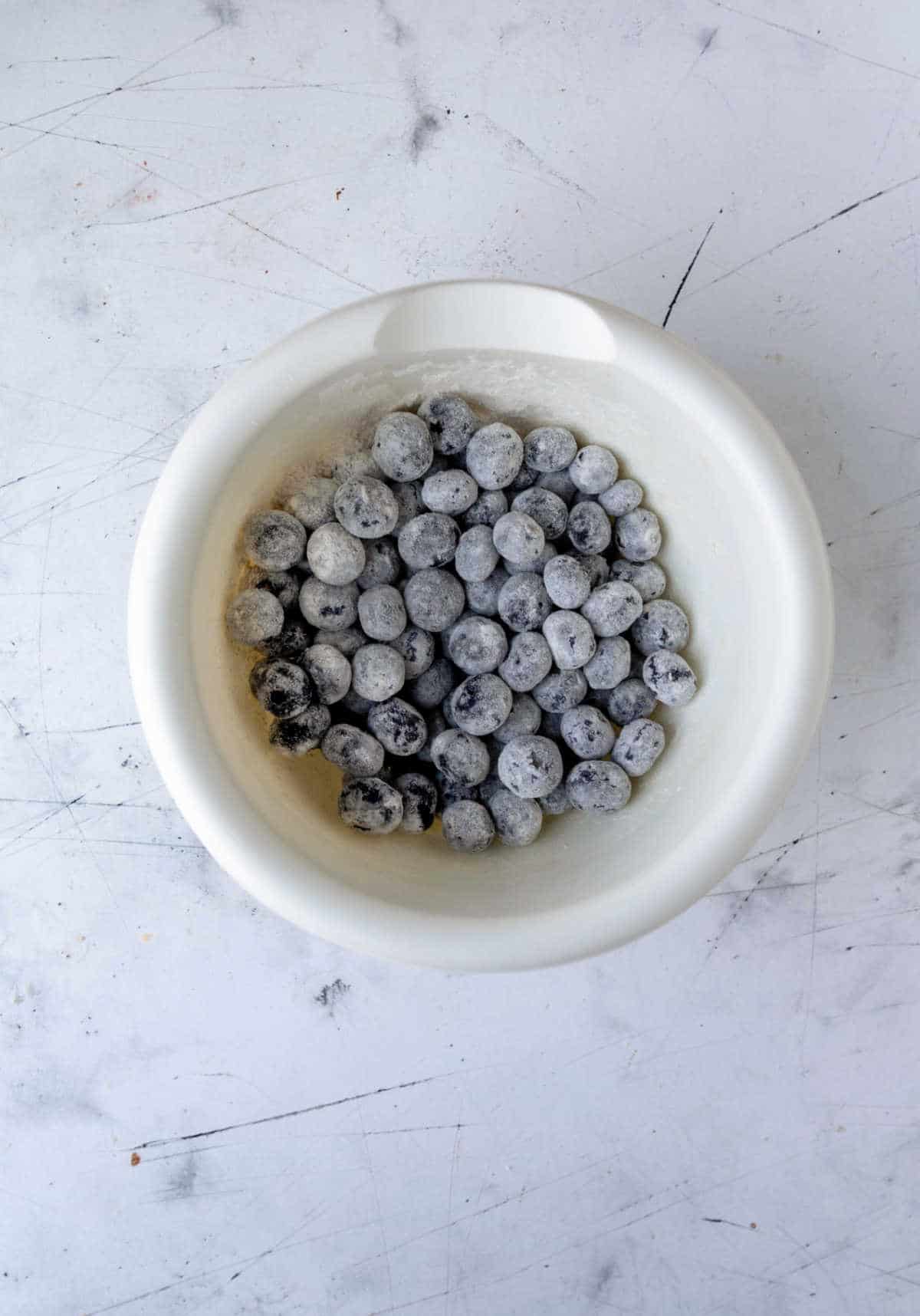 Flour coated blueberries in a bowl. 