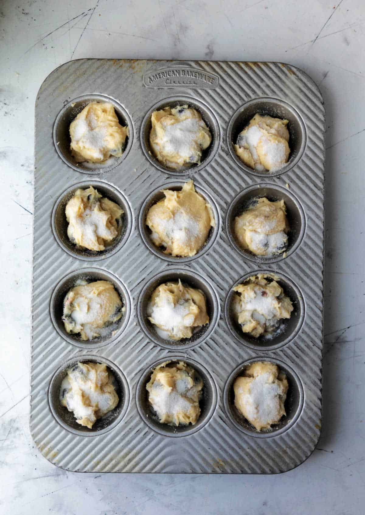Blueberry muffin batter in a muffin tin. 