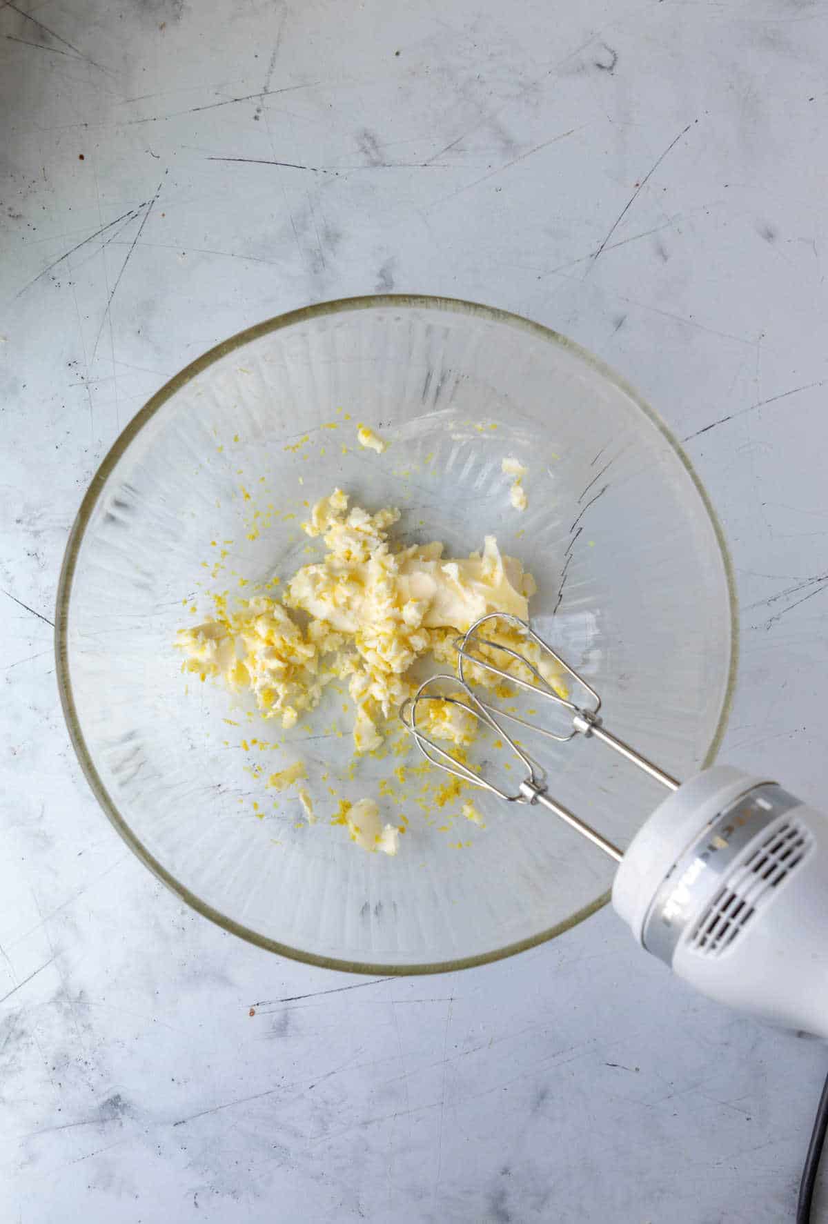 Hand mixer beating butter and lemon and sugar together. 