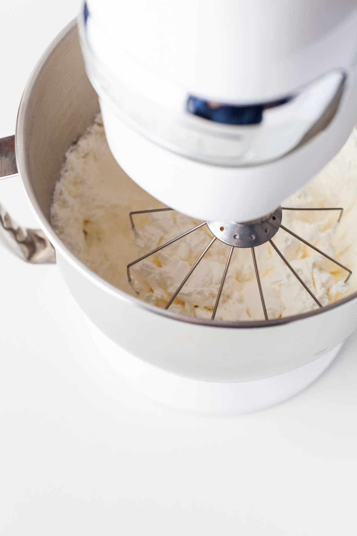 Whipped cream mixing in a stand mixer.