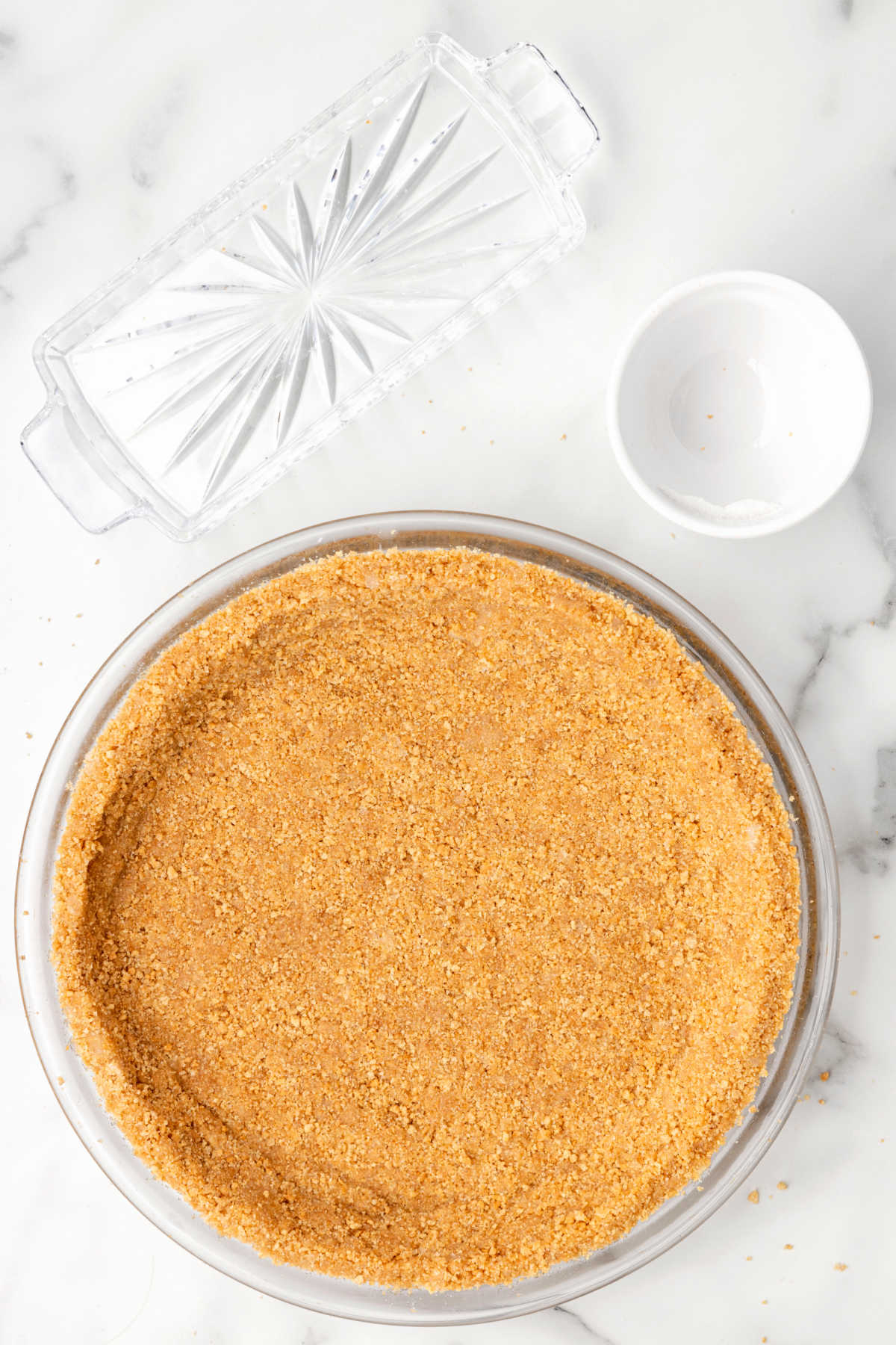 Graham cracker crust next to two empty dishes. 