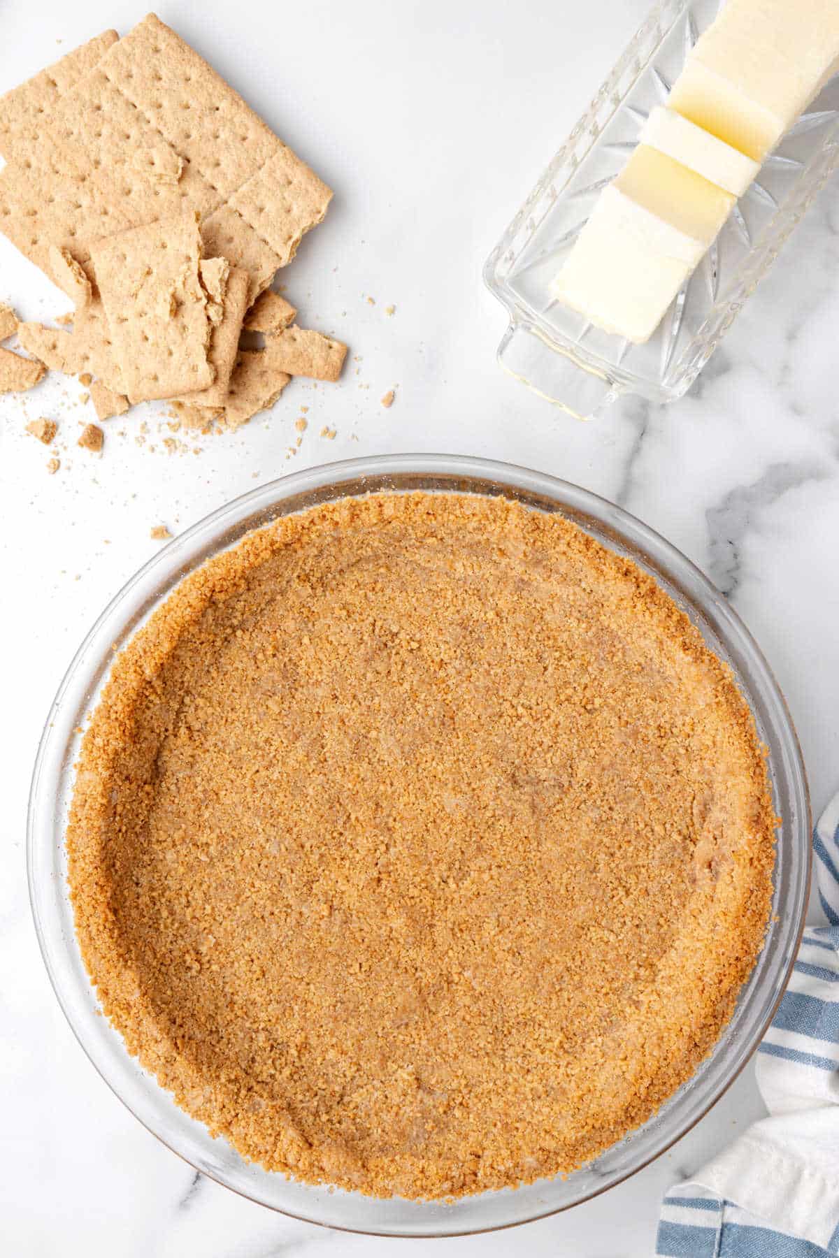 A graham cracker pie crust next to broken graham crackers.