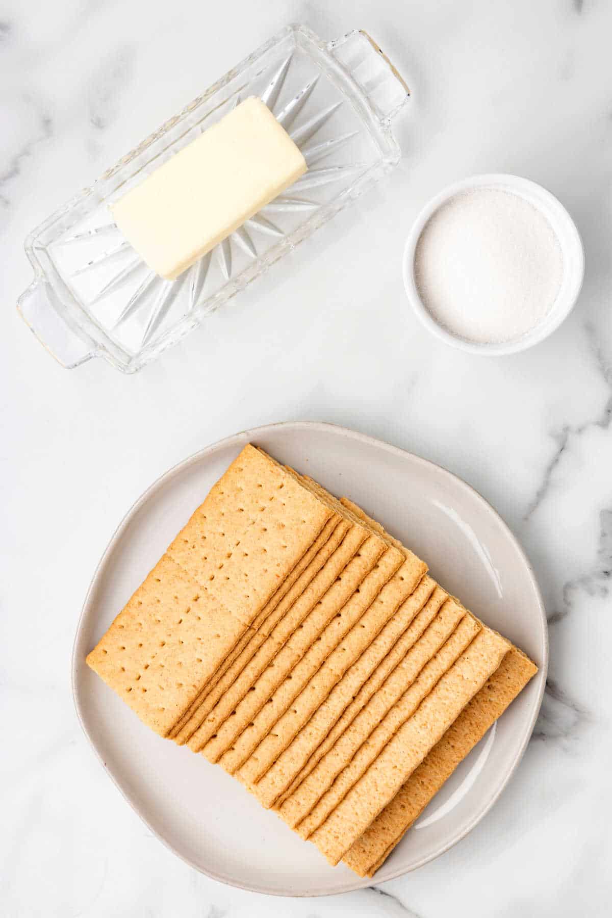 Graham crackers, sugar, and butter in dishes.