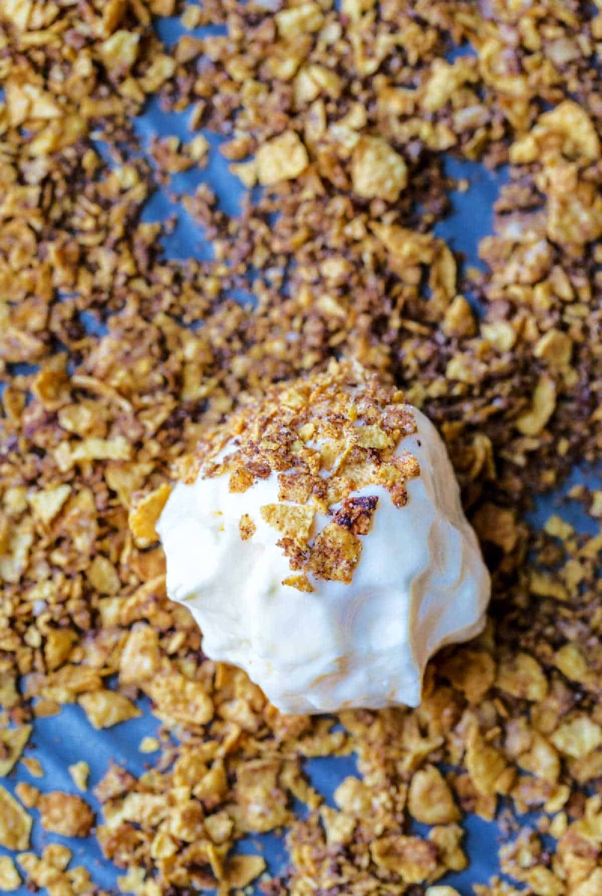 A scoop of vanilla ice cream rolled in cornflake coating. 