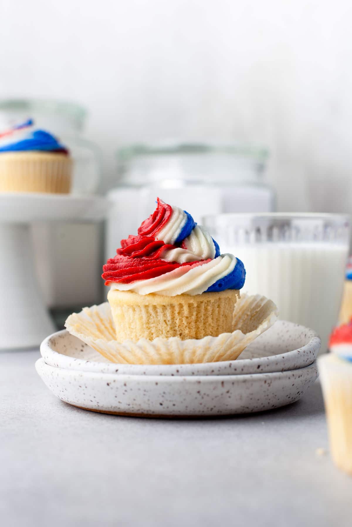 A red white and blue cupcakes with the wrapper undone on a white plate.
