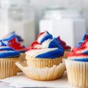 Red white and blue cupcakes on pieces of white parchment paper.