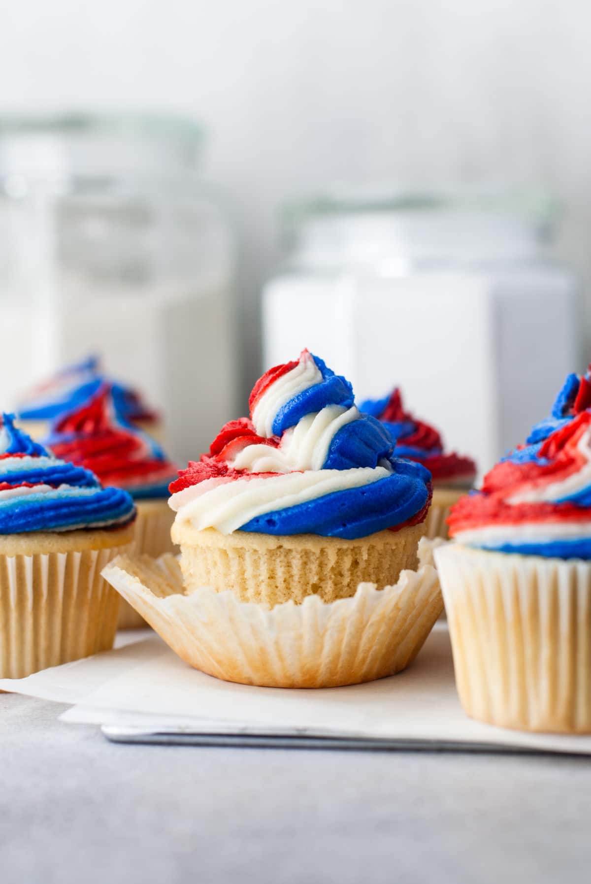 Red white and blue cupcakes on pieces of white parchment paper. 