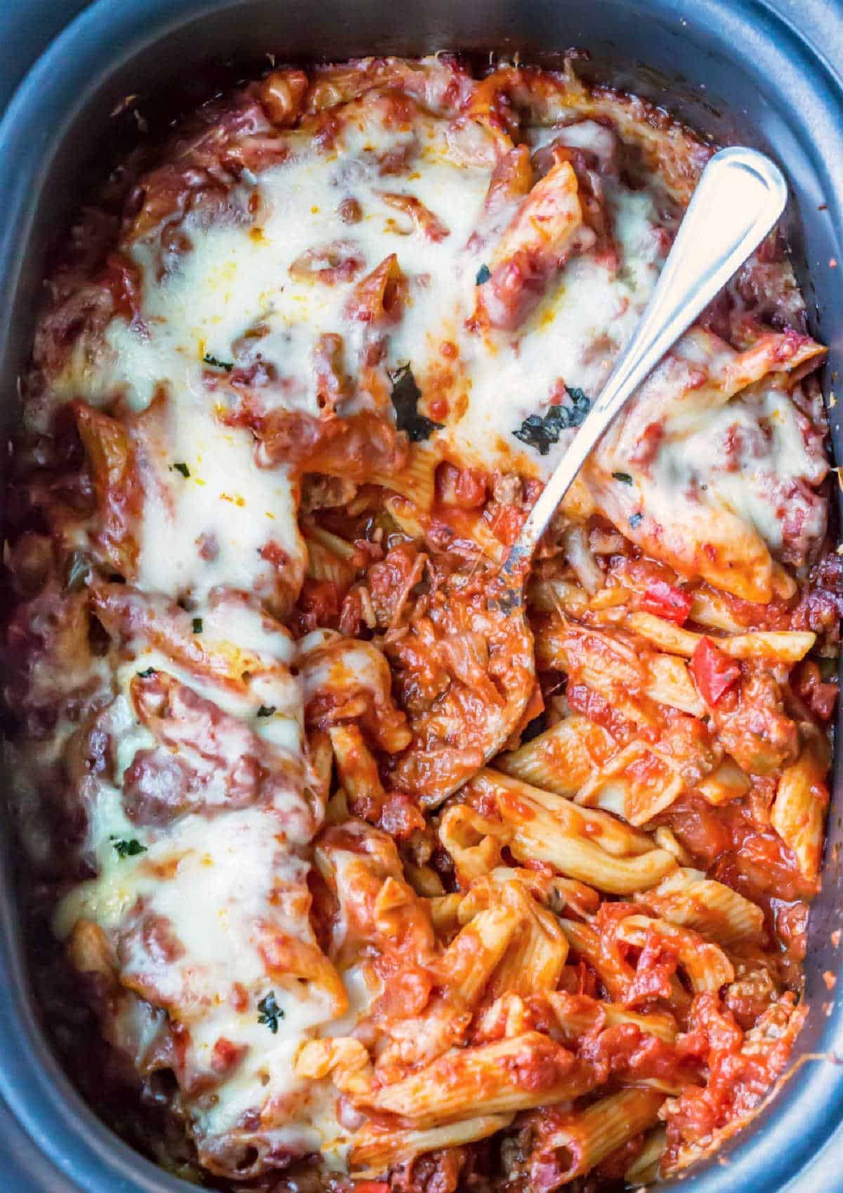 Slow cooker baked ziti with a silver spoon in it. 