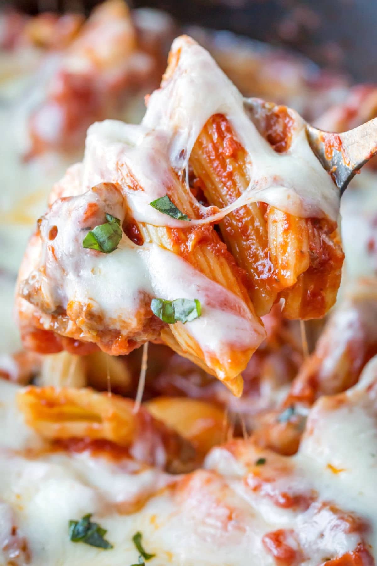 A spoon scooping up slow cooker baked ziti. 