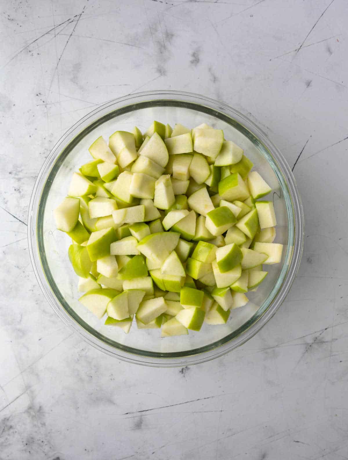 Chopped green apple in a glass mixing bowl. 