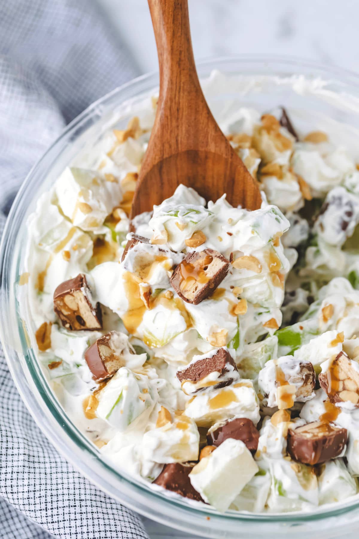 A wooden spoon on a bowl of Snickers salad.