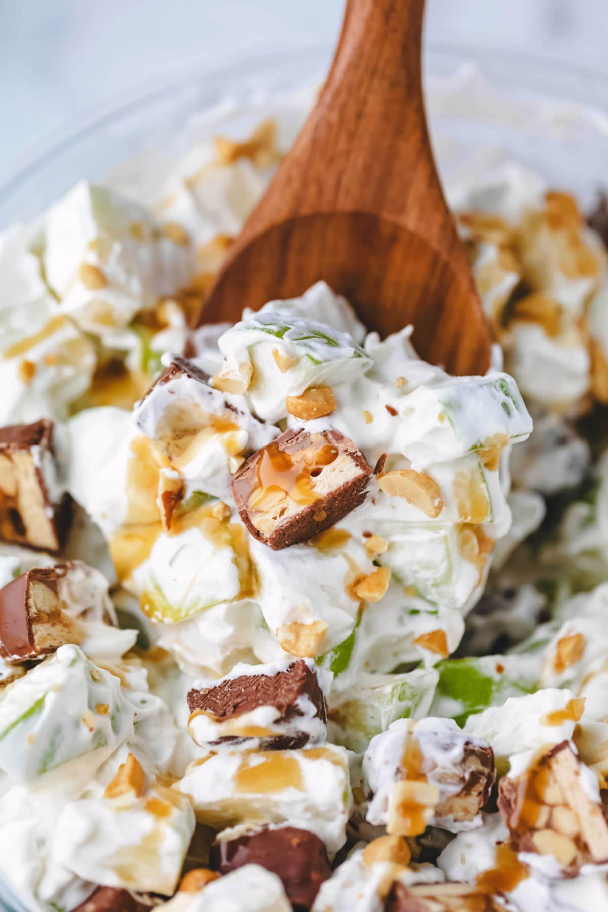 A wooden spoon scooping up snickers salad.