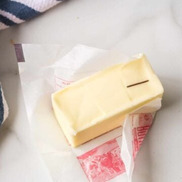 Partially unwrapped stick of butter on a counter.