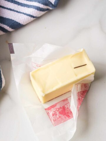 Partially unwrapped stick of butter on a counter.