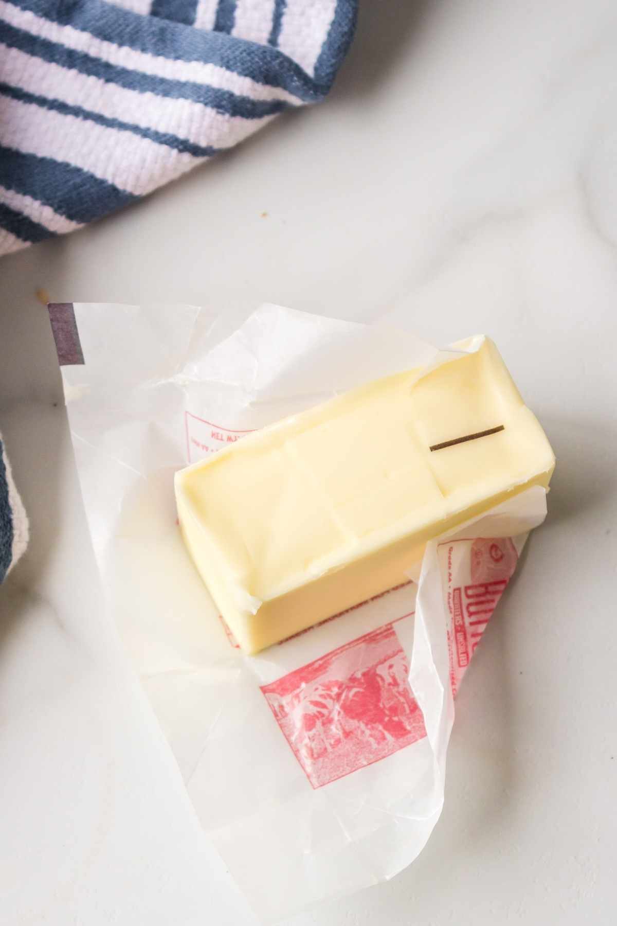 Partially unwrapped stick of butter on a counter. 