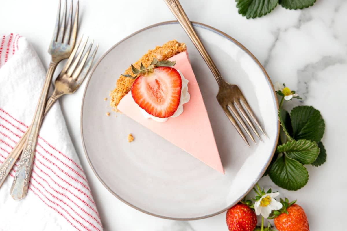 Slice of strawberry jello pie on a plate with a fork. 