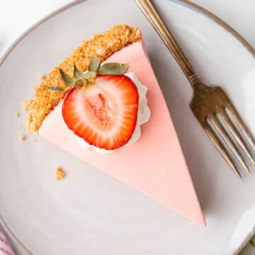 A slice of strawberry jello pie topped with whipped cream and a sliced strawberry.