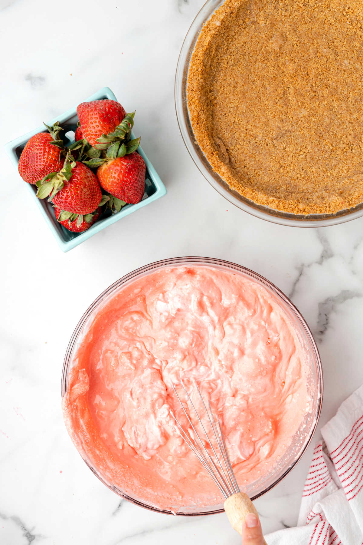 Cool whip and jello mixture in a glass mixing bowl. 