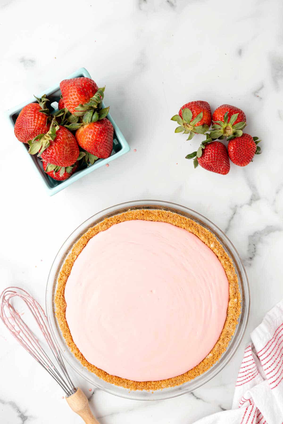 Strawberry jello pie next to a carton of strawberries.