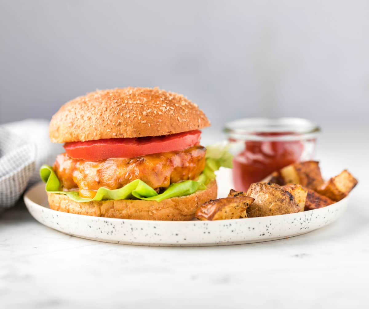 Turkey burger next to diced potatoes and ketchup. 