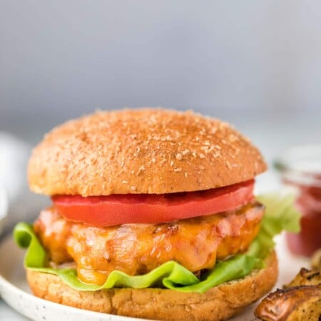 Turkey burger on a whole wheat bun with lettuce and tomato on it.