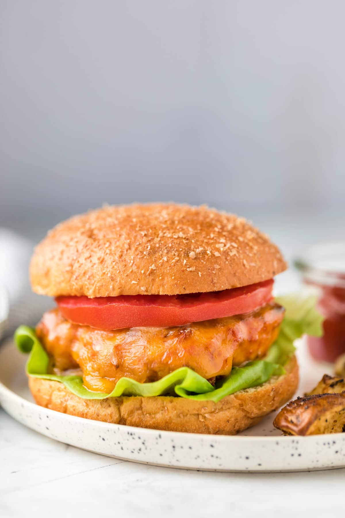 Turkey burger on a whole wheat bun with lettuce and tomato on it. 