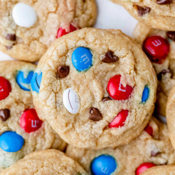 Stacks of red white and blue M&M cookies on a piece of white parchment paper.