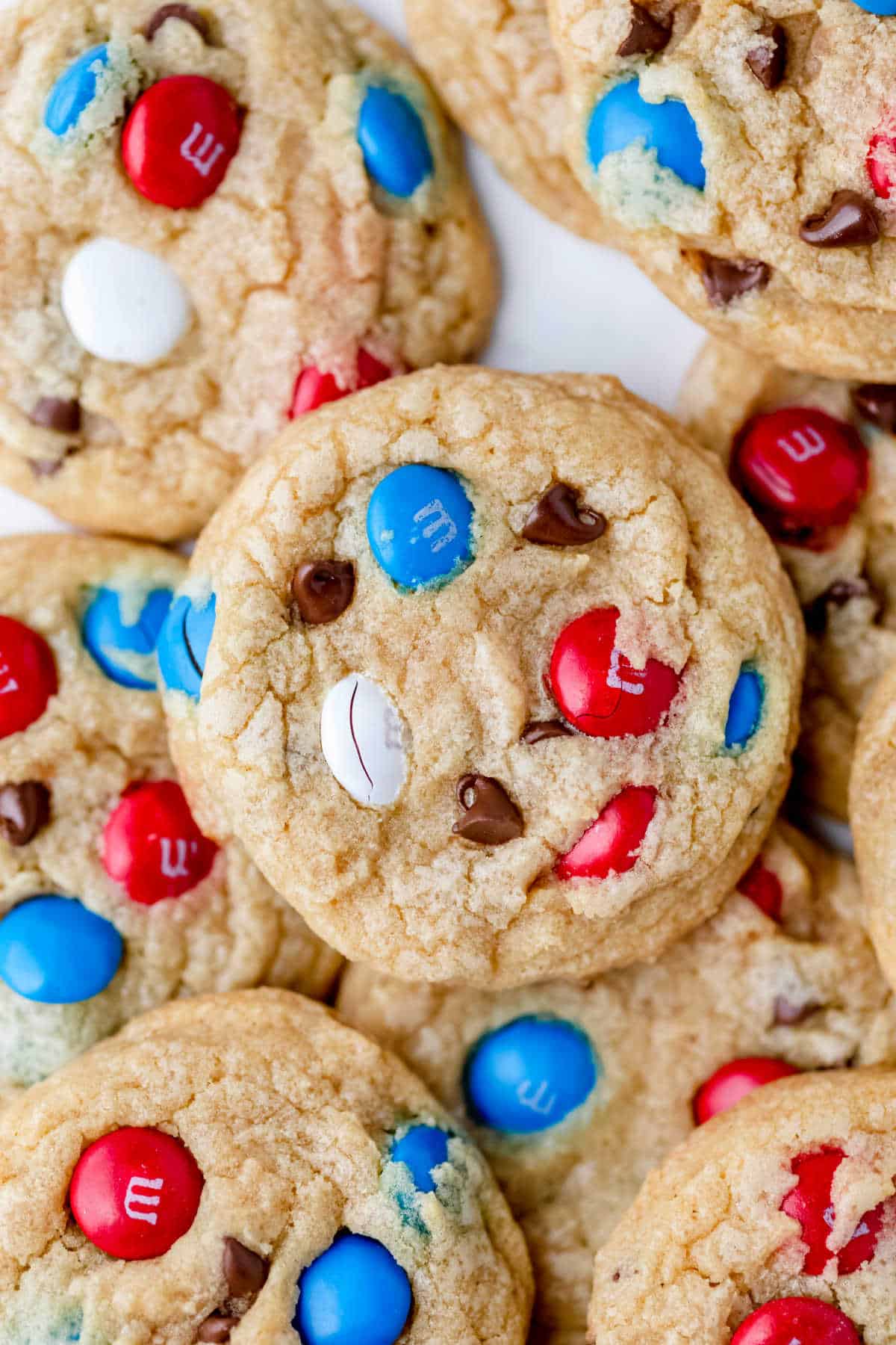 Stacks of red white and blue M&M cookies on a piece of white parchment paper. 