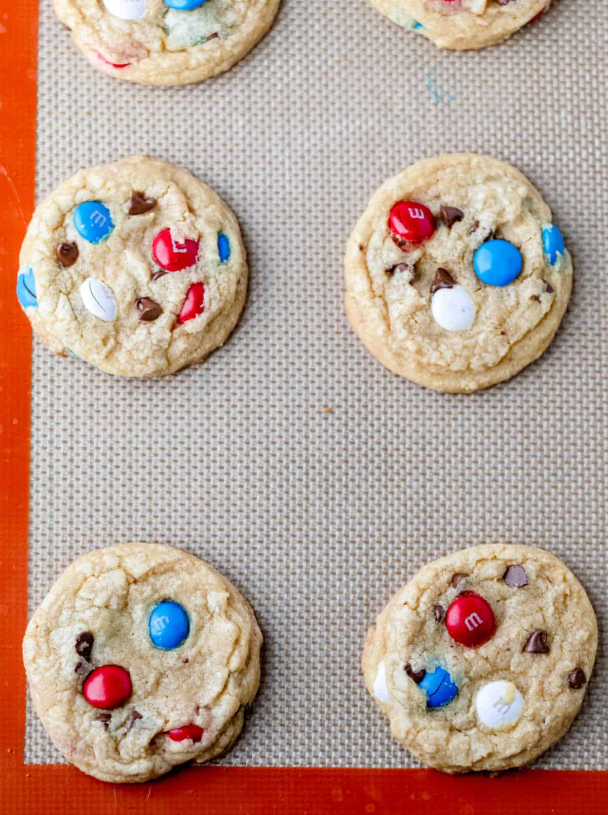 Baked red white and blue M&M cookies on a baking sheet.