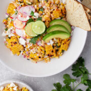 A bowl of Mexican street corn salad next to a dish of the salad.