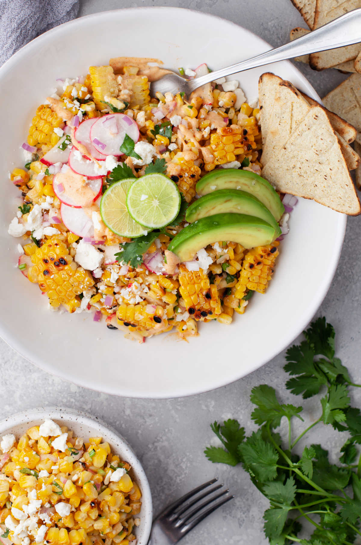 A bowl of Mexican street corn salad next to a dish of the salad.