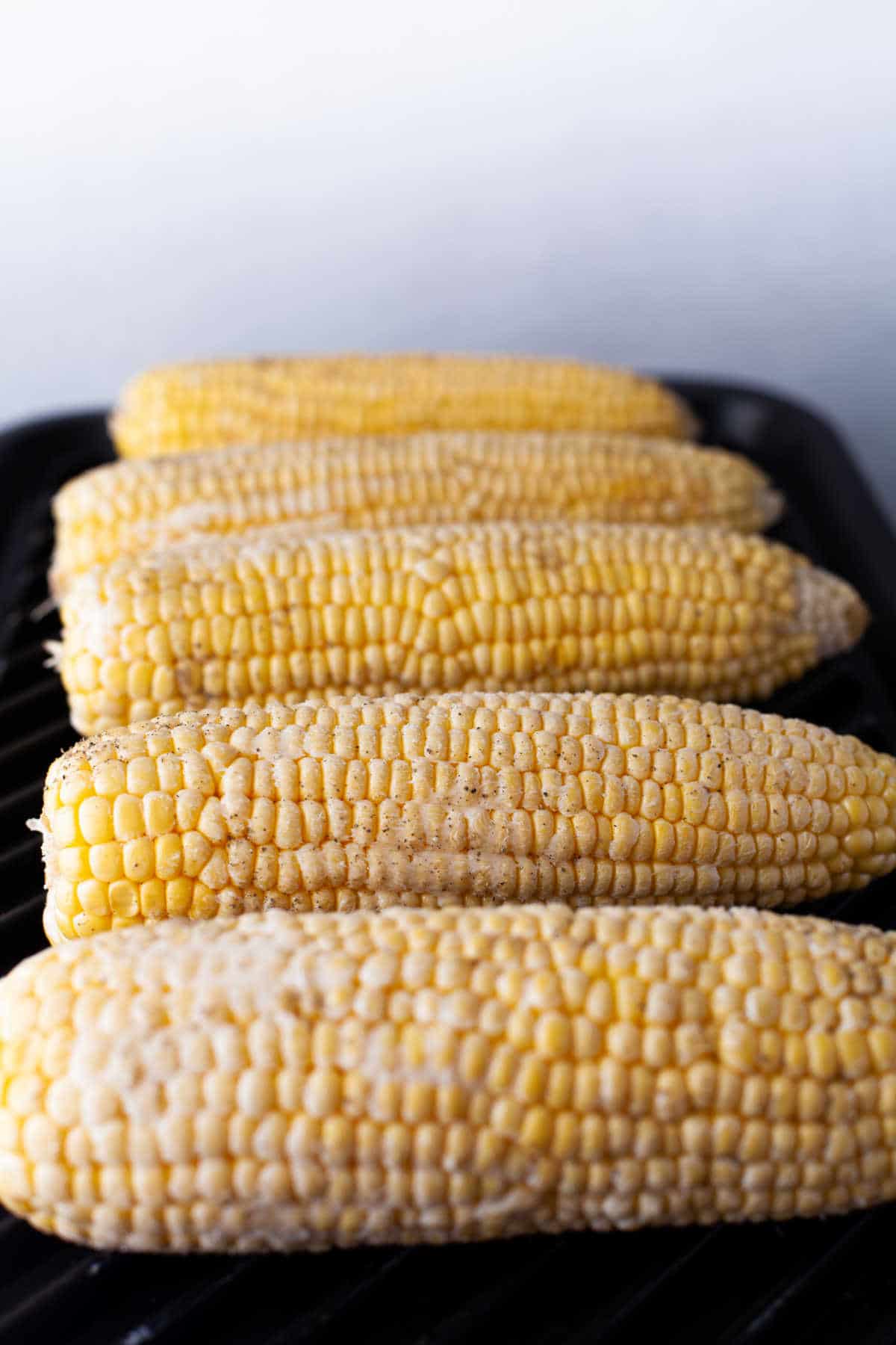 Ears of corn grilling on a grill pan. 