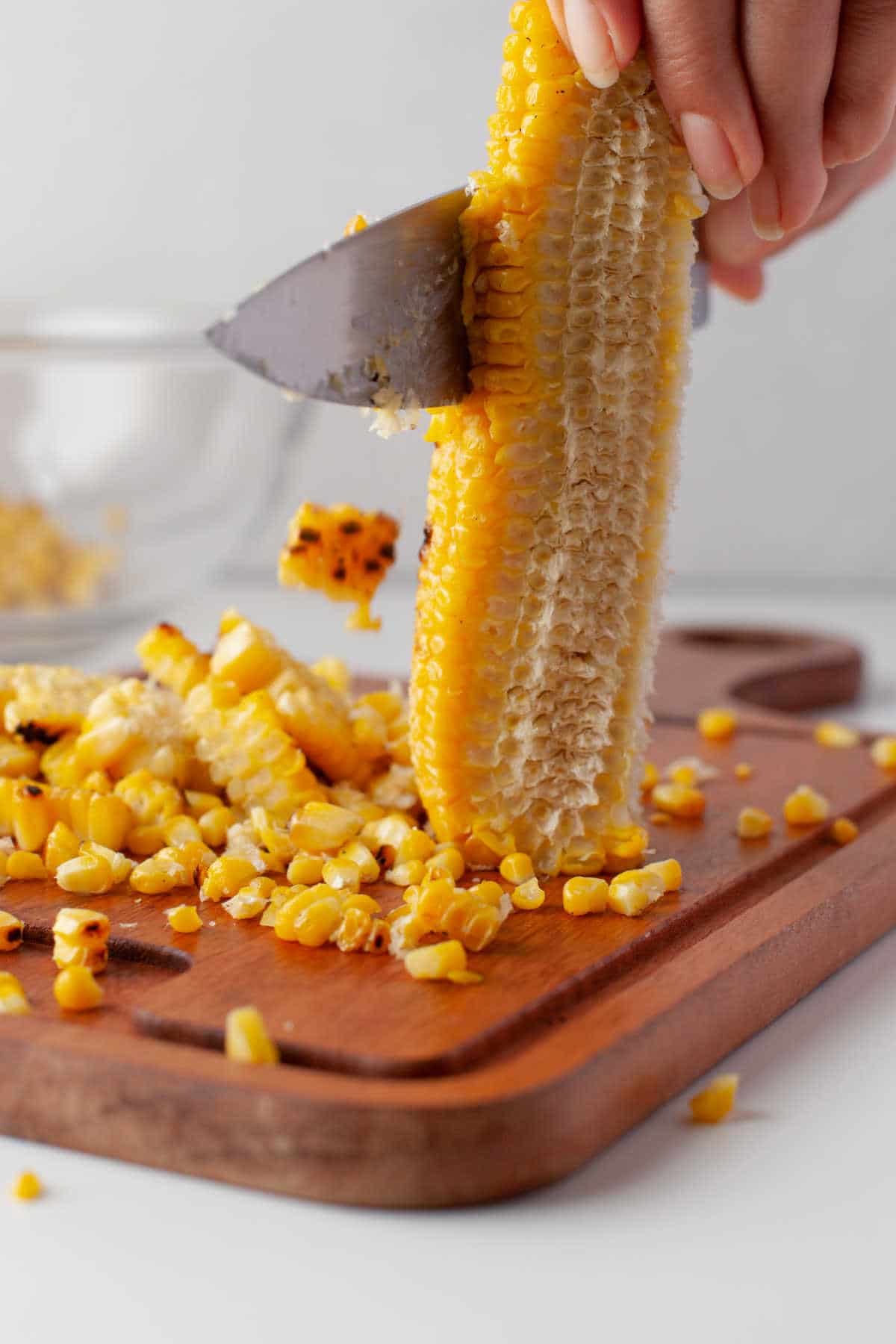 A knife cutting the kernels from an ear of corn. 