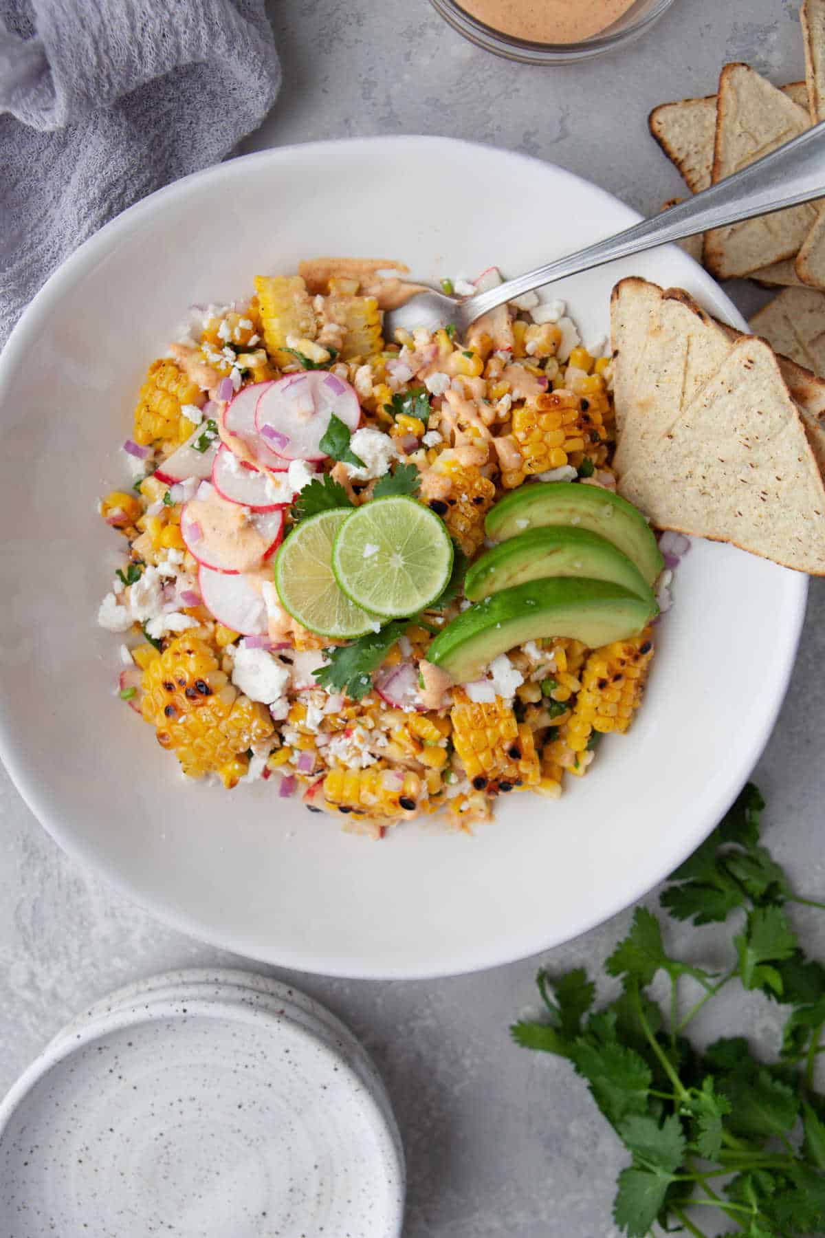 A big bowl of Mexican street corn salad with a fork in it. 