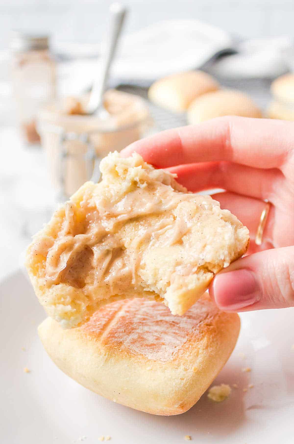 A hand holding up half a roll topped with cinnamon honey butter.