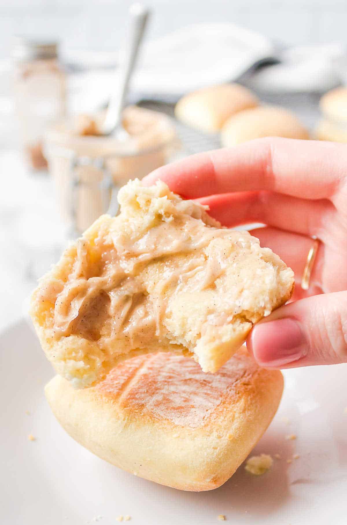 A hand holding up half a roll topped with cinnamon honey butter. 