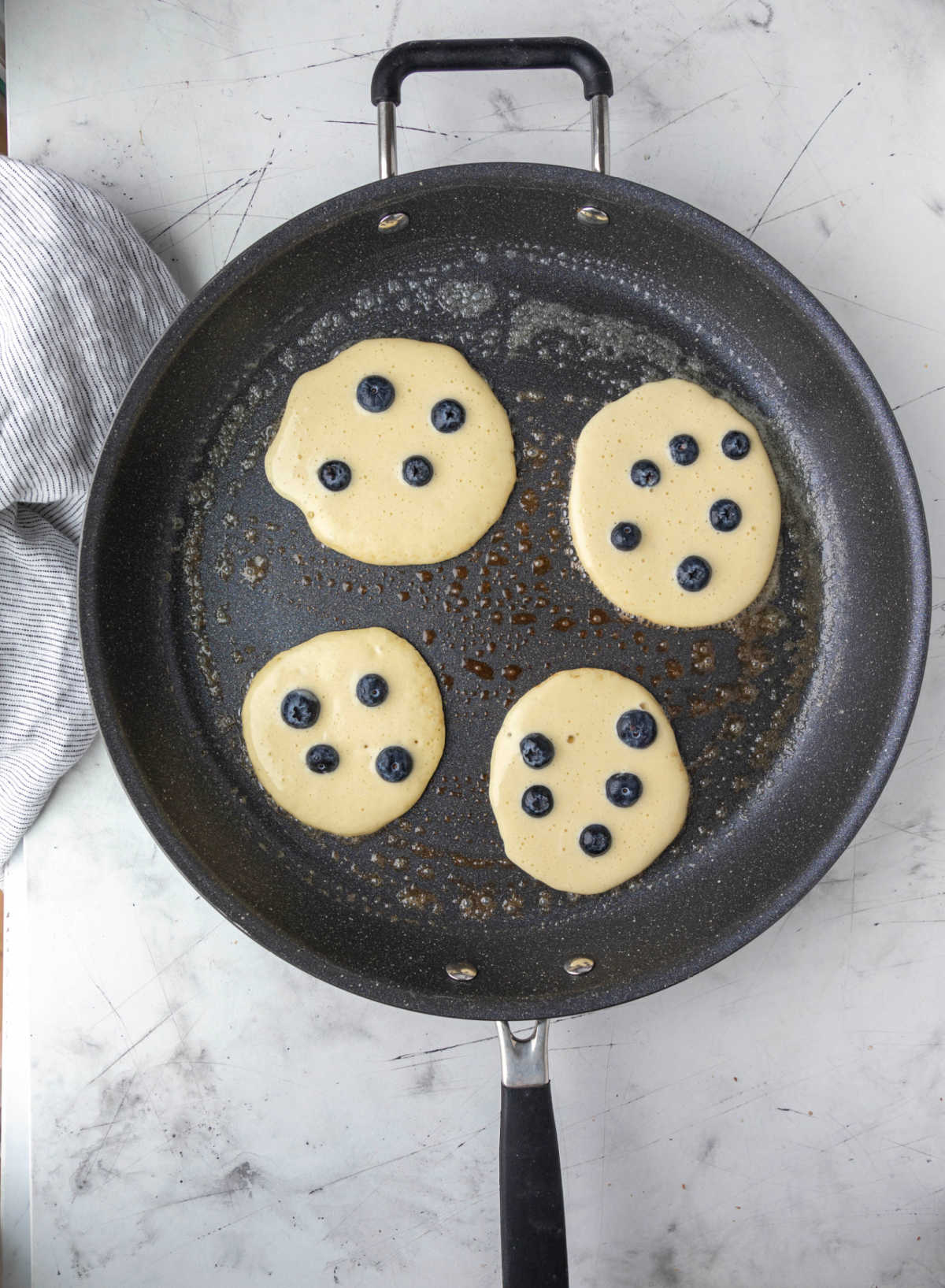 Blueberry pancakes cooking in a skillet. 