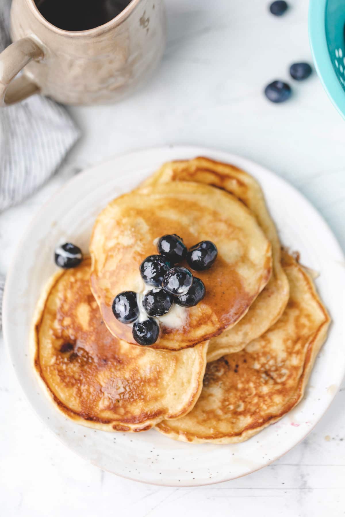 Overhead photo of blueberry pancakes topped with fresh blueberries and syrup.