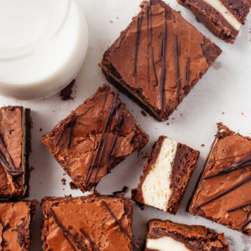 Frozen cheesecake brownies next to a glass of milk.