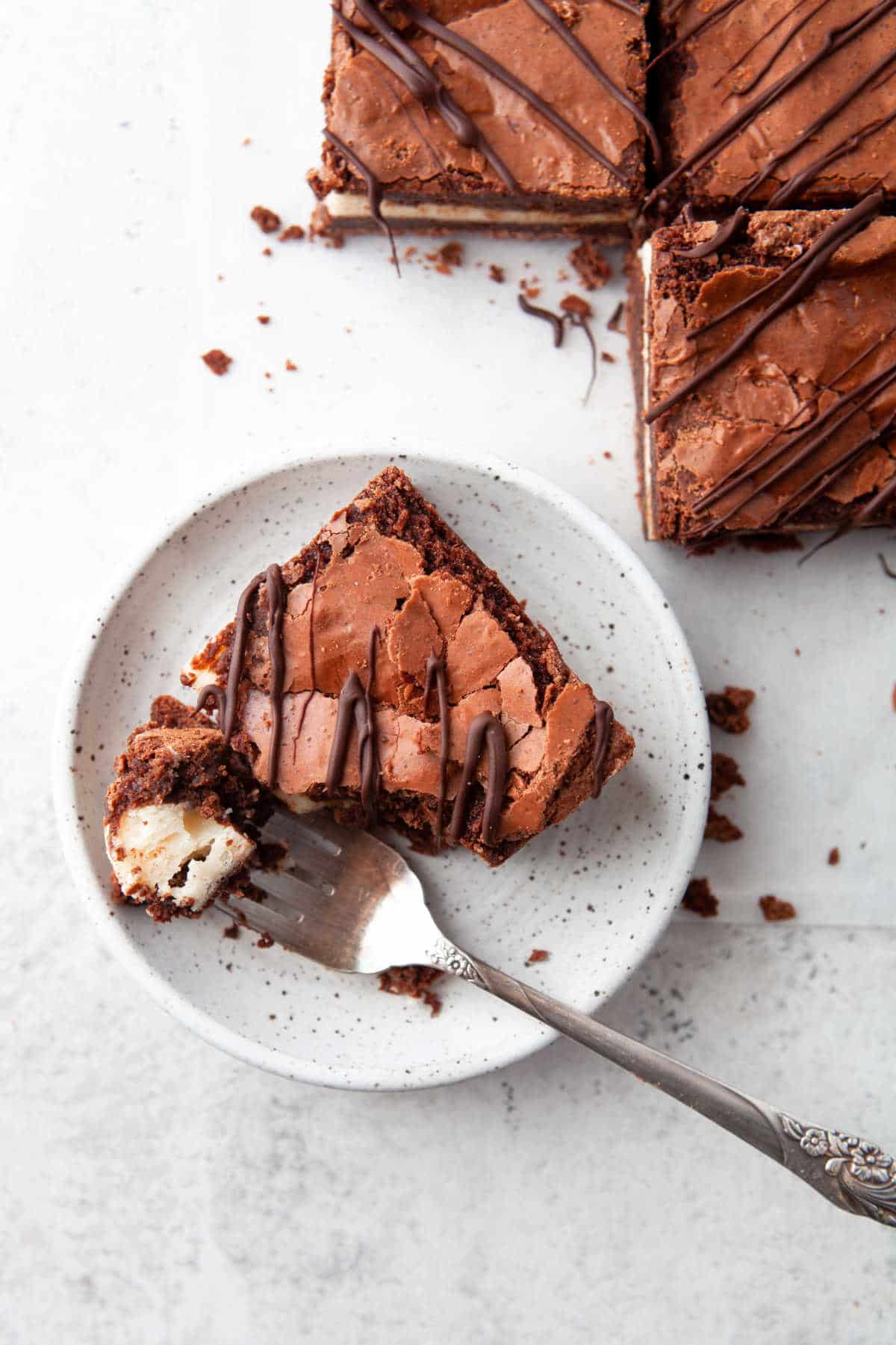 A fork taking a bite of a frozen cheesecake brownie. 